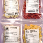 Frucht-Bundle mit Ananas, Banane, Erdbeere und Mango in Doypacks auf violettem Hintergrund