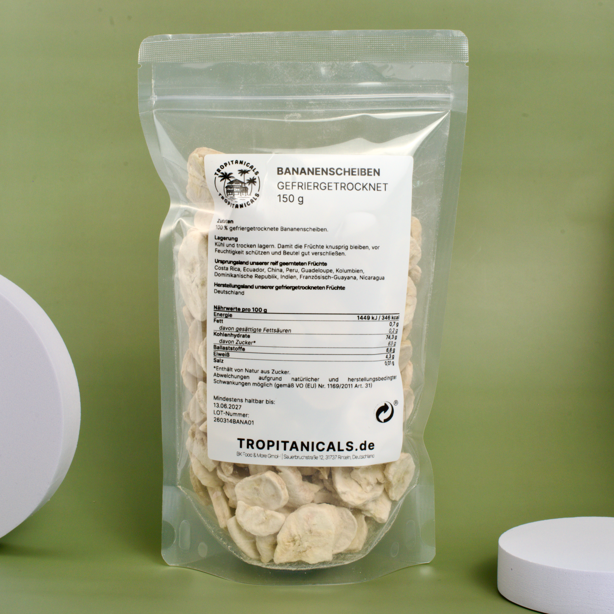 Gefriergetrocknete Bananenscheiben vor grünem Hintergrund mit weißen Dekoelementen
